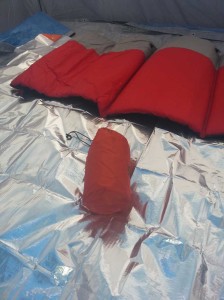 Rolled sleeping pad in front of self inflating sleeping pad.